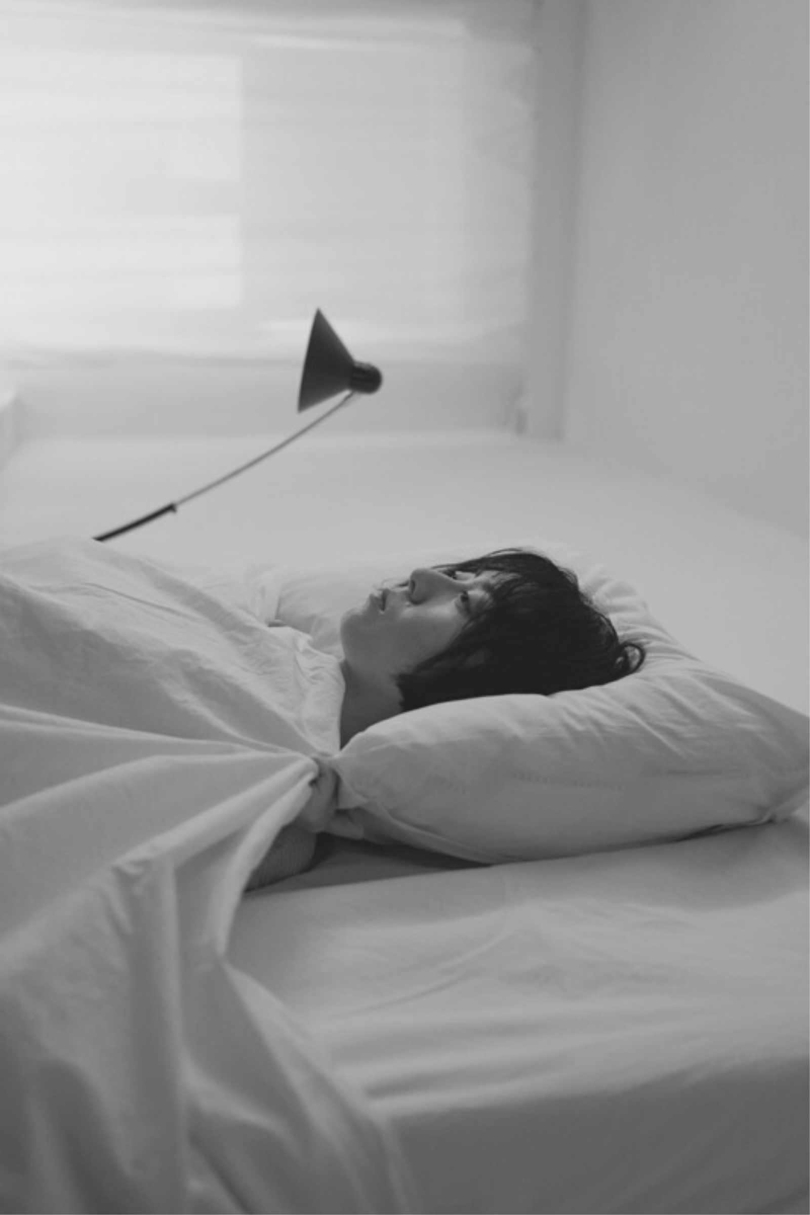 Depressed Asian person lying in bed